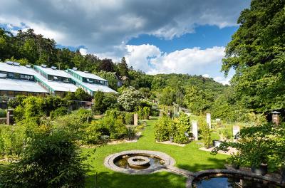 Greenhouses and garden beds at the Botanical Garden of the City of Neuchâtel on a sunny day.